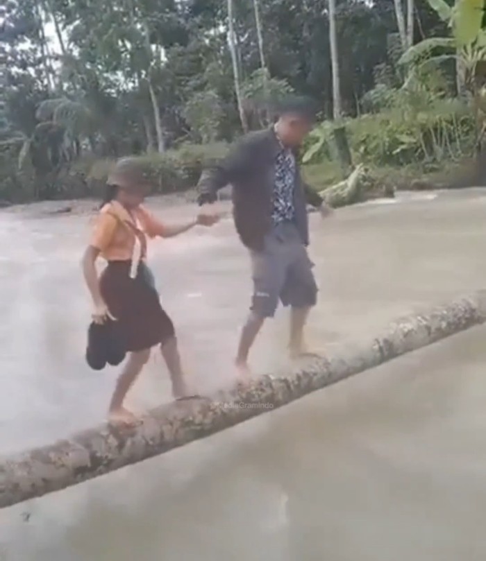 siswa SD di Nias Selatan nyeberang sungai pakai batang kayu. (Foto: Tangkapan layar)