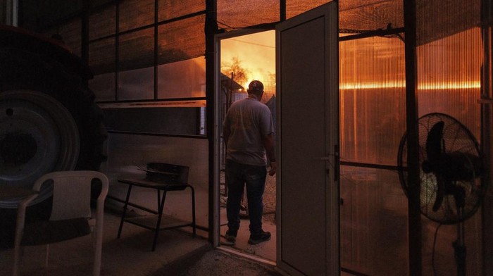 A local resident watches the wildfire in Avantas village, near Alexandroupolis town, in the northeastern Evros region, Greece, Monday, Aug. 21, 2023. Gale-force winds are fanning the flames of wildfires across Greece, including 53 new blazes that broke out early Monday amid hot, dry and windy weather that has sucked moisture from vegetation. (AP Photo/Achilleas Chiras)