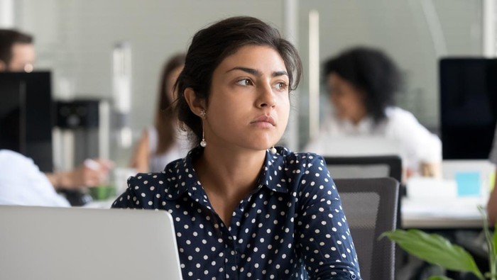 Thoughtful indian business woman looking away feeling bored pensive thinking of problem solution in office with laptop, serious hindu employee searching new ideas at work unmotivated about dull job