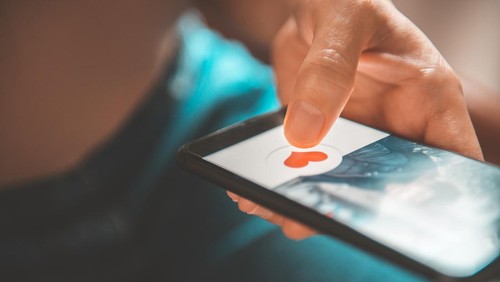 Finger of woman pushing heart icon on screen in mobile smartphone application. Online dating app, valentines day concept.