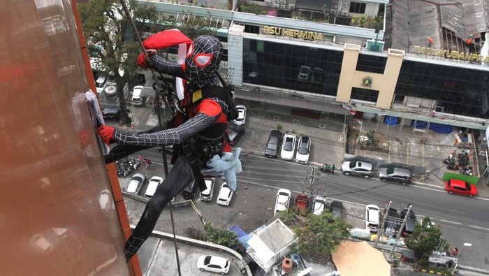 Pekerja berkostum Spiderman membersihkan kaca di Hotel Aria Gajayana, Malang, Jawa Timur, Rabu (23/8/2023). Aksi di gedung berlantai 12 tersebut dilakukan untuk memberi kenyamanan bagi tamu sekaligus menarik perhatian wisatawan yang berkunjung di Kota Malang. ANTARA FOTO/Ari Bowo Sucipto/rwa.