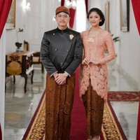 Erina Gudono mengenakan kebaya klasik bernuansa peach saat berpose bersama Kaesang Pangarep di Istana Negara. Kebaya rancangan Wiranti Kurnia ini dipadukan dengan kain batik wiron. Finalis Puteri Indonesia 2022 ini pun memakai sanggul Jawa klasik yang anggun. Foto: Instagram/@erinagudono
