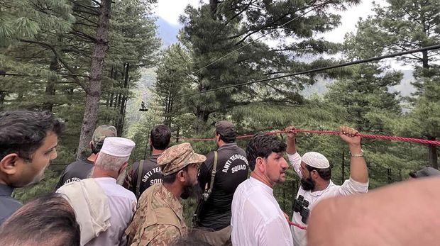 In this image taken from video, a cable car carrying six children and two adults dangles hundreds of meters above the ground in the remote Battagram district, Khyber Pakhtunkhwa, Pakistan on Tuesday, Aug. 22, 2023. The cable car malfunctioned, trapping the occupants for hours before rescuers arrived in helicopters to try to free them. (AP Photo)