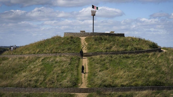 Potret Taman Pedesaan di London yang Dibangun dari Limbah People stand on top of a mound in Northala Fields Country Park in London, Monday, Aug. 21, 2023. Northala fields is a country park that consists of ponds and four large earth mounds built using waste from the original Wembley Stadium and the building of the White City Westfield shopping centre. The mounds help to reduce noise pollution, provide a view point and are an interesting landmark for the area in west London. (AP Photo/Kirsty Wigglesworth)