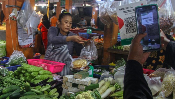 Pembeli bertransaksi menggunakan pembayaran nontunai Quick Response Code Indonesian Standard (QRIS) saat berbelanja di Pasar Limapuluh, Pekanbaru, Riau, Rabu (23/8/2023). Pasar Limapuluh merupakan salah satu dari tujuh pasar rakyat di Kota Pekanbaru yang menerapkan pembayaran nontunai melalui QRIS untuk bertransaksi. ANTARA FOTO/Rony Muharrman/rwa.