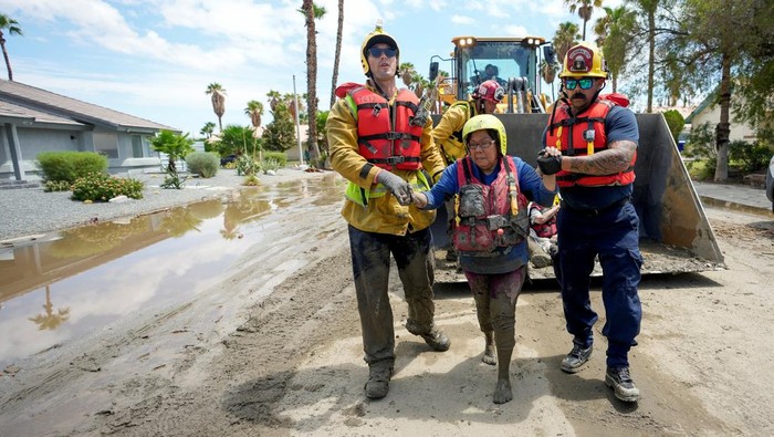 Warga California Terdampak Badai Hilary Dievakuasi dengan Buldoser Firefighters and emergency medical personnel move a resident, who was trapped in a care home overnight, to an ambulance following Tropical Storm Hilary in Cathedral City, California, U.S., August 21, 2023. REUTERS/Bryan Woolston