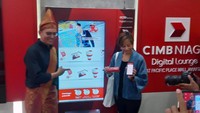 Head of Marketing, Brand and Customer Experience CIMB Niaga Toni Darusman (kiri) mendampingi pengguna aplikasi CIMB THAI Digital Banking dari Thailand usai bertransaksi menggunakan metode pembayaran QRIS Cross-Border di mesin OCTO Vending, Digital Lounge CIMB Niaga, di Jakarta, Rabu (23/8/2023).  