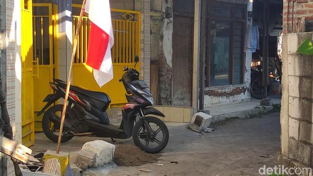Dua batu besar yang disemen permanen di depan rumah Masriah dan sepeda motor yang diparkir menghalangi akses utama mobil ke rumah Wiwik.