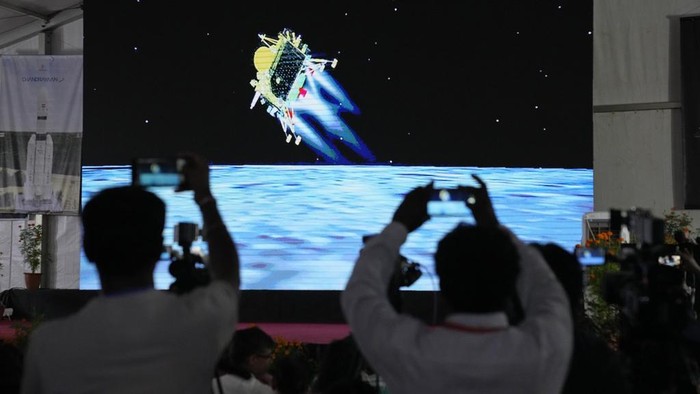 Journalists film the live telecast of spacecraft Chandrayaan-3 landing on the moon at ISROs Telemetry, Tracking and Command Network facility in Bengaluru, India, Wednesday, Aug. 23, 2023. India lands a spacecraft near the moon’s south pole, becoming the fourth country to touch down on the lunar surface. (AP Photo/Aijaz Rahi)