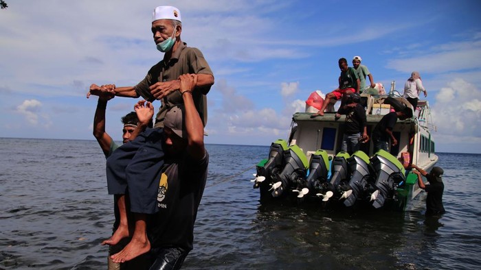 Seorang penumpang menggendong anaknya saat turun dari kapal cepat setibanya di Desa Mateketen, Pulau Makian, Kabupaten Halmahera Selatan, Maluku Utara, Kamis (24/8/2023). Ketiadaan infrastruktur dermaga penyeberangan antarpulau di daerah itu mengharuskan penumpang terpaksa turun ke air laut untuk berjalan kurang lebih 25 meter menuju tepi pantai, dan menyulitkan pemilik kapal melakukan bongkar muat barang. ANTARA FOTO/Andri Saputra/rwa.