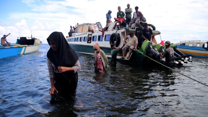 Seorang penumpang menggendong anaknya saat turun dari kapal cepat setibanya di Desa Mateketen, Pulau Makian, Kabupaten Halmahera Selatan, Maluku Utara, Kamis (24/8/2023). Ketiadaan infrastruktur dermaga penyeberangan antarpulau di daerah itu mengharuskan penumpang terpaksa turun ke air laut untuk berjalan kurang lebih 25 meter menuju tepi pantai, dan menyulitkan pemilik kapal melakukan bongkar muat barang. ANTARA FOTO/Andri Saputra/rwa.