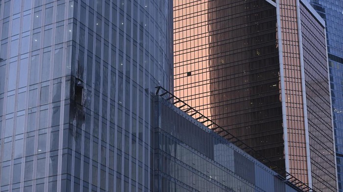 Workers clean a part of a damaged skyscraper in the 