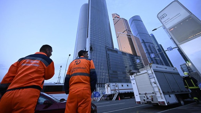 Workers clean a part of a damaged skyscraper in the 