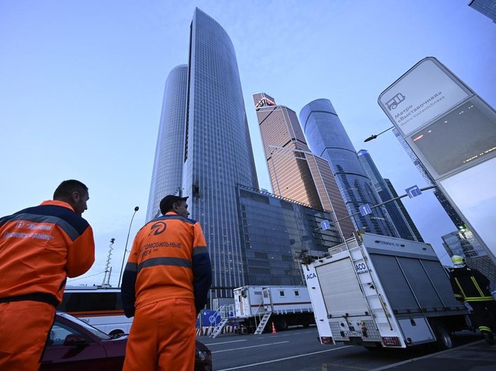 Workers clean a part of a damaged skyscraper in the 