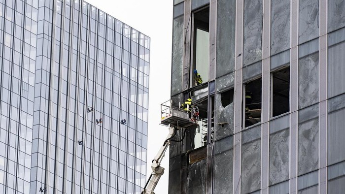 Workers clean a part of a damaged skyscraper in the 