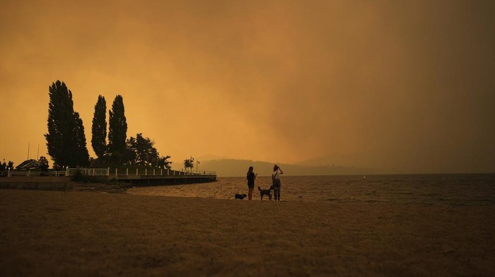 The McDougall Creek wildfire burns on the mountainside above a lakefront home in West Kelowna, B.C., on Friday, August 18, 2023. (Darryl Dyck/The Canadian Press via AP)