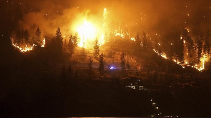 Potret Mencekam Kebakaran Hutan Terburuk di Kanada The McDougall Creek wildfire burns on the mountainside above a lakefront home in West Kelowna, B.C., on Friday, August 18, 2023. (Darryl Dyck/The Canadian Press via AP)
