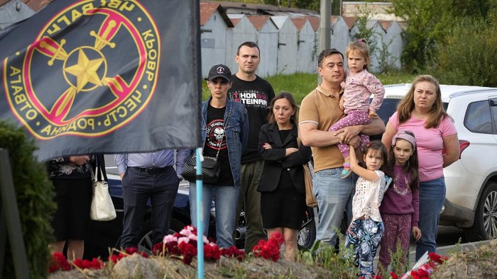 A man lights candles at a informal memorial next to the former 'PMC Wagner Centre' in St. Petersburg, Russia, Thursday, Aug. 24, 2023. Russia's civil aviation agency says mercenary leader Yevgeny Prigozhin was aboard a plane that crashed north of Moscow. (AP Photo/Dmitri Lovetsky)
