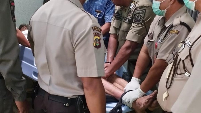 Anggota Satpol PP Badung mengamankan bule Rusia, RA (tertidur), yang mengamuk di vila di Desa Tibubeneng, Badung, Bali, Jumat pagi (25/8/2023).