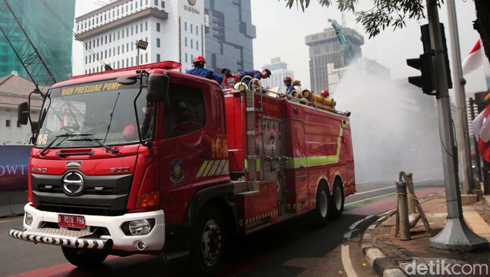 Petugas pemadam kebakaran menyemprotkan air disepanjang jalan MH Thamrin, Jakarta Pusat. Penyemprotan air dilakukan untuk mengurangi polusi di Jakarta.