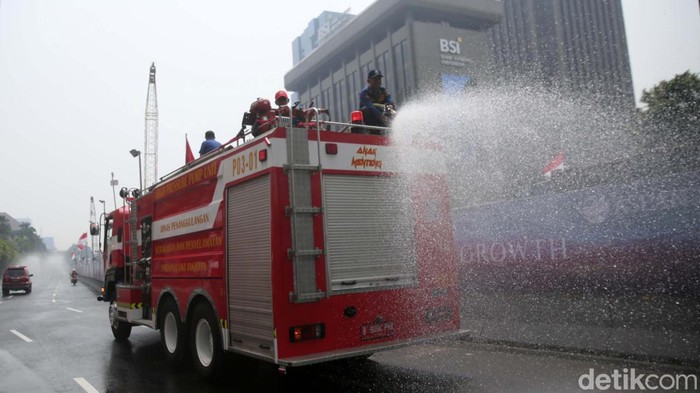 Petugas pemadam kebakaran menyemprotkan air disepanjang jalan MH Thamrin, Jakarta Pusat. Penyemprotan air dilakukan untuk mengurangi polusi di Jakarta.