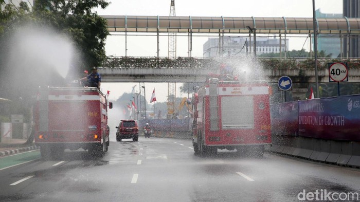 Petugas pemadam kebakaran menyemprotkan air disepanjang jalan MH Thamrin, Jakarta Pusat. Penyemprotan air dilakukan untuk mengurangi polusi di Jakarta.