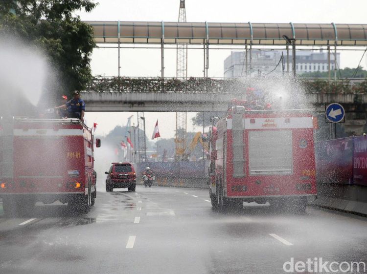 Kurangi Polusi Udara, Pemadam Kebakaran Semprotkan Air ke Jalan
