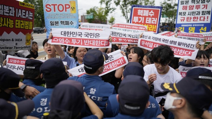 Massa Tolak Pembuangan Limbah Nuklir di Korsel Ditangkap Polisi Protesters hold signs during a rally to denounce to release treated radioactive water into the sea from the damaged Fukushima nuclear power plant, outside of a building which houses Japanese Embassy, in Seoul, South Korea, Thursday, Aug. 24, 2023. The operator of the tsunami-wrecked Fukushima Daiichi nuclear power plant says it has begun releasing its first batch of treated radioactive water into the Pacific Ocean β a controversial step, but a milestone for Japan's battle with the growing radioactive water stockpile. The letters read