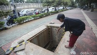 Seorang bocah terlihat menunjukkan lokasi tutup dorong-gorong yang hilang dicuri di trotoar depan TPU Menteng Pulo, Jakarta, Jumat (25/8/2023).
