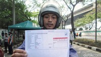 Warga menunjukan hasil uji emisi kendaraannya.  