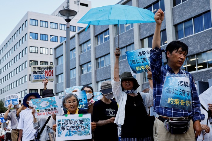 Protesters hold signs that read 