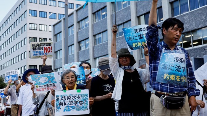 Protesters hold signs that read 