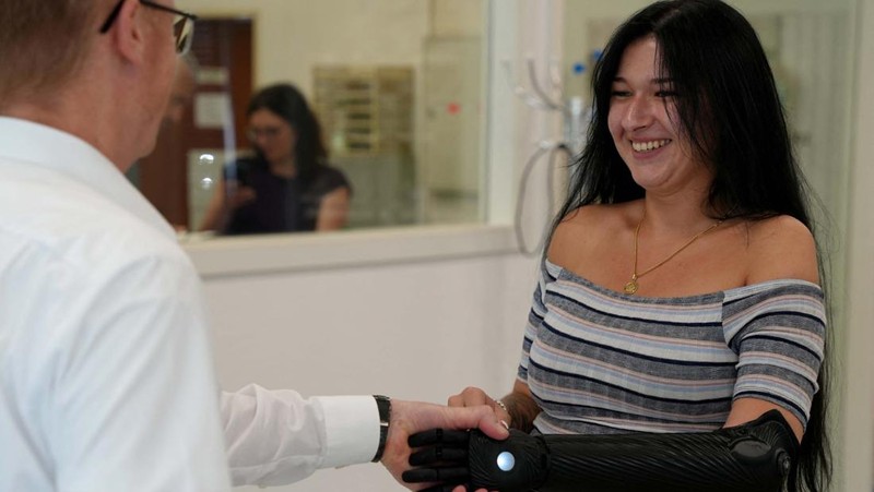 Orthopaedic technician Mike Unmacht of medical supplies company Lammert Scherer holds the bionic arm for Dominika Frycz, who received her new Open Bionics arm, among the first of its kind funded through health insurance and created with 3d printing, in Mainz, Germany, August 18, 2023. The 25-year-old who was born without a lower left arm had a bionic arm in the past, but decided against it because the weight of the arm and very limited movement caused more problems than it solved.  REUTERS/Max Schwarz