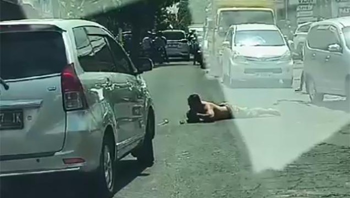 Tangkapan layar pria viral yang tiduran dan mengacungkan senjata tajam kepada pengendara di Jalan Raya Pengosekan Ubud, Gianyar, Bali.
