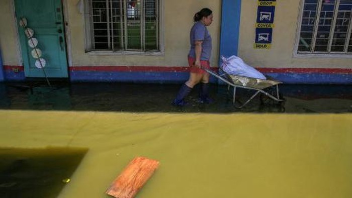 A teacher pushes a wheelbarrow with a sack of wet books as they salvage items from classrooms at a flooded school in Calumpit, Bulacan province on August 19, 2023. (Photo by Earvin Perias / AFP)