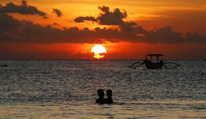 FILE- In this Jan. 18, 2017, file photo, photographers take photos of a tourist couples wedding at the famous Kuta beach during sunset in Bali, Indonesia. According to a 2016 survey from wedding site The Knot, the average cost of an international destination wedding is $25,800. That figure may be within your event budget, but for guests, international airfare and multinight lodging could be out of reach. (AP Photo/Firdia Lisnawati, File)