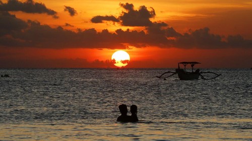 FILE- In this Jan. 18, 2017, file photo, photographers take photos of a tourist couples wedding at the famous Kuta beach during sunset in Bali, Indonesia. According to a 2016 survey from wedding site The Knot, the average cost of an international destination wedding is $25,800. That figure may be within your event budget, but for guests, international airfare and multinight lodging could be out of reach. (AP Photo/Firdia Lisnawati, File)