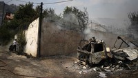 Asap juga mengepul dari mobil dan bangunan yang terbakar. AP Photo/Thanassis Stavrakis.  