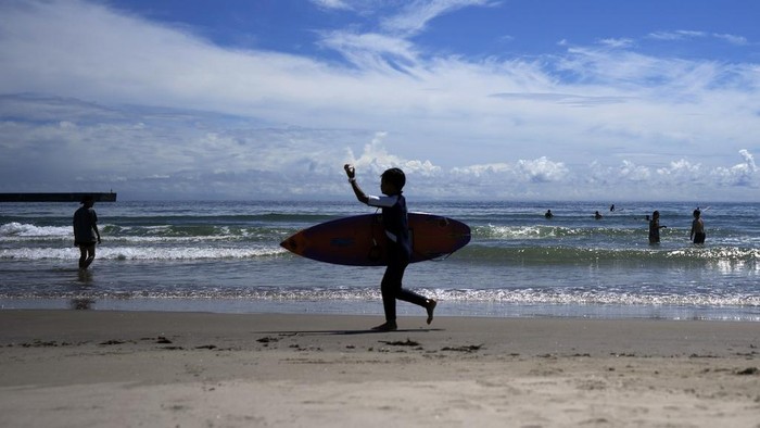 People walk on the beach to surf at the Yotsukura beach, about 30 kilometers (about 18 miles) south of the Fukushima Daiichi nuclear power plant, damaged by a massive March 11, 2011, earthquake and tsunami, in Iwaki, northeastern Japan, Saturday, Aug. 26, 2023. The Fukushima Daiichi nuclear power plant started releasing treated and diluted radioactive wastewater into the Pacific Ocean on last Thursday. (AP Photo/Eugene Hoshiko)