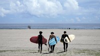 Orang-orang berjalan di pantai untuk berselancar di pantai Yotsukura, di Iwaki, timur laut Jepang, Sabtu (26/8/2023).   