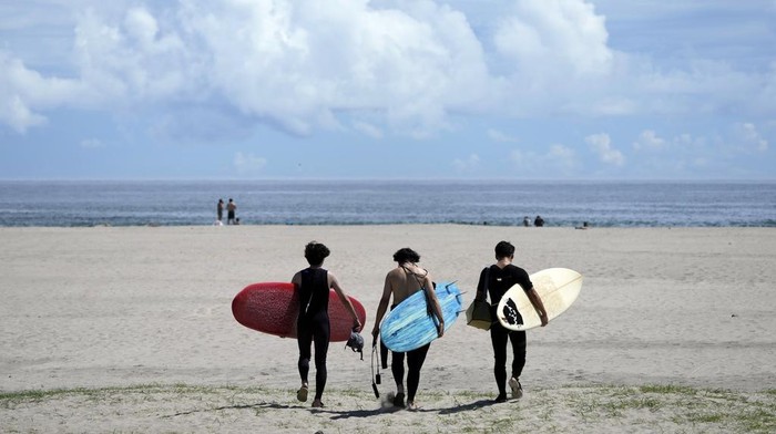 Suasana Pantai Yotsukura Jepang Setelah Pembuangan Limbah Nuklir ke Laut People walk on the beach to surf at the Yotsukura beach, about 30 kilometers (about 18 miles) south of the Fukushima Daiichi nuclear power plant, damaged by a massive March 11, 2011, earthquake and tsunami, in Iwaki, northeastern Japan, Saturday, Aug. 26, 2023. The Fukushima Daiichi nuclear power plant started releasing treated and diluted radioactive wastewater into the Pacific Ocean on last Thursday. (AP Photo/Eugene Hoshiko)