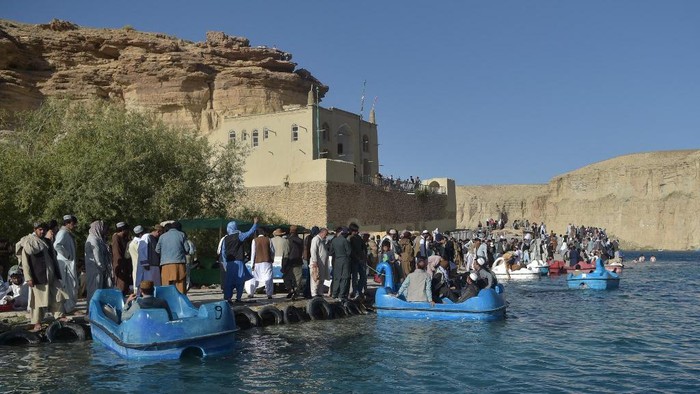In this picture taken on July 14, 2022, Afghan tourists cool off and enjoy boat rides at Ban e-Amir Lake in Bamyan province. (Photo by Ahmad SAHEL ARMAN / AFP)