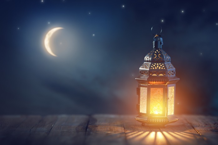 Ornamental Arabic lantern with burning candle glowing at night. Festive greeting card, invitation for Muslim holy month bulan berkat Kareem.n