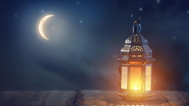 Ornamental Arabic lantern with burning candle glowing at night. Festive greeting card, invitation for Muslim holy month Ramadan Kareem.