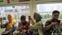Sejumlah penumpang mengabadikan gedung-gedung di sepanjang jalur LRT Jabodebek. 
