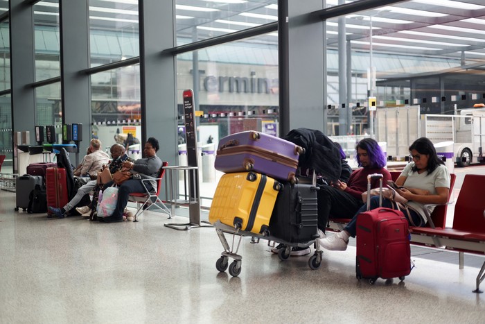 A British Airways staff member speaks to passengers at Heathrow Airport, as Britains National Air Traffic Service (NATS) restricts UK air traffic due to a technical issue causing delays, in London, Britain, August 28, 2023. REUTERS/Hollie Adams
