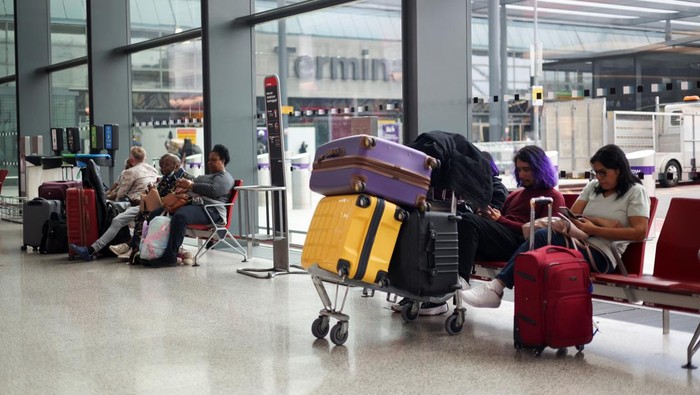 A British Airways staff member speaks to passengers at Heathrow Airport, as Britains National Air Traffic Service (NATS) restricts UK air traffic due to a technical issue causing delays, in London, Britain, August 28, 2023. REUTERS/Hollie Adams