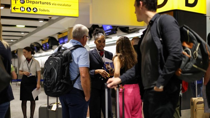 Potret Penumpang Terlantar di Bandara Inggris Akibat Gangguan Teknis A British Airways staff member speaks to passengers at Heathrow Airport, as Britain's National Air Traffic Service (NATS) restricts UK air traffic due to a technical issue causing delays, in London, Britain, August 28, 2023. REUTERS/Hollie Adams