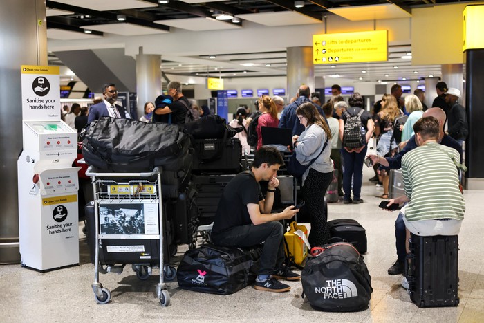 A British Airways staff member speaks to passengers at Heathrow Airport, as Britains National Air Traffic Service (NATS) restricts UK air traffic due to a technical issue causing delays, in London, Britain, August 28, 2023. REUTERS/Hollie Adams