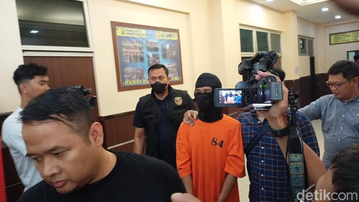 Tetangga penjudi yang menusuk suami istri di Tebet, Jaksel, berbaju tahanan dan diborgol.